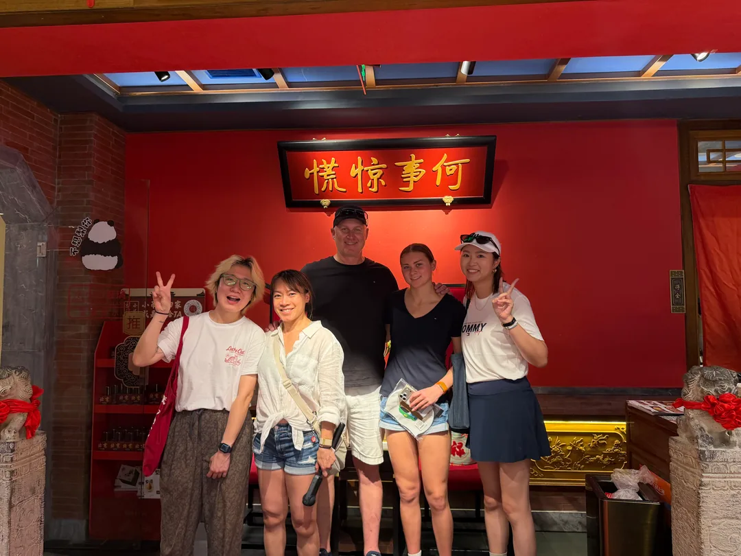 Five people posing together in front of a red wall in Shanghai.