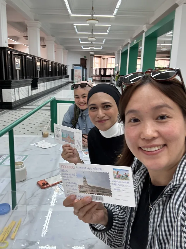 A Buddy and guests holding postcards in a photo together.